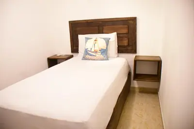 a bedroom with a large white bed and two tables at Hostal Marina Samana in Santa Bárbara de Samaná