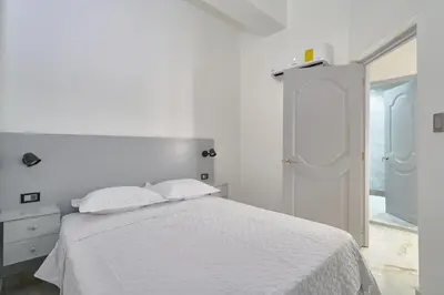 a white bedroom with a white bed with two pillows at spectacular sea view in Santo Domingo