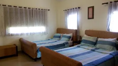 a bedroom with two beds and a chair and windows at Green Paradise in Juan Dolio