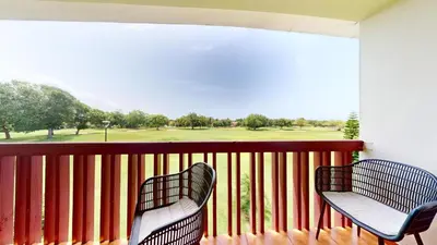 two chairs on a balcony with a view of a golf course at Green Paradise in Juan Dolio