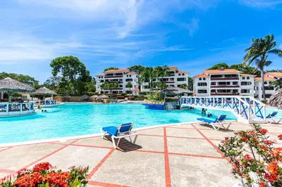 a swimming pool at a resort with blue chairs at Monte Vista Apartments in Sosúa