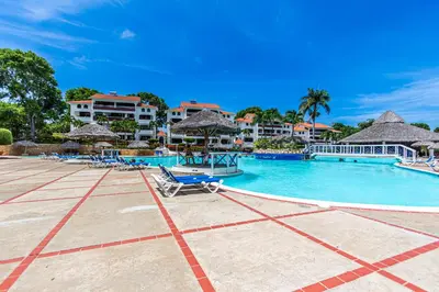 a pool at a resort with chairs and umbrellas at Monte Vista Apartments in Sosúa
