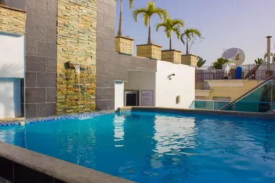 a large blue swimming pool with palm trees in the background at Modern and centric Apartment with pool and gym at Downtown in Santo Domingo