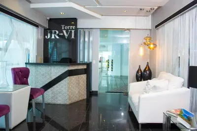 a hotel room with a white bed and a bar at Modern and centric Apartment with pool and gym at Downtown in Santo Domingo