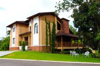 a house with two chairs in front of it at Vista del Campo Country Club & Villas in Jarabacoa