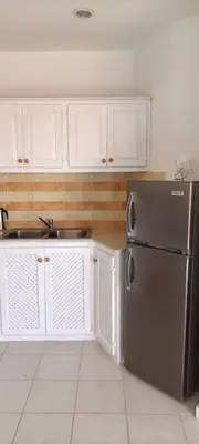 a kitchen with a stainless steel refrigerator and white cabinets at El Rinconcito Caribeño in La Laguna