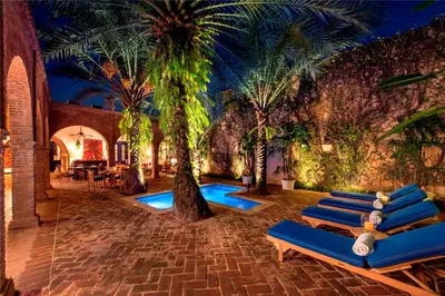 a courtyard with palm trees and blue lounge chairs at Casas del XVI in Santo Domingo