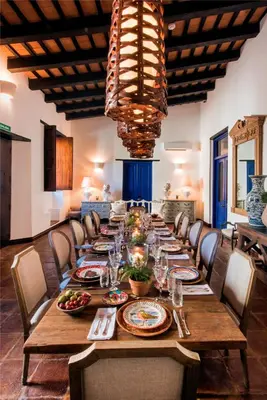 a long wooden table with chairs and a large chandelier at Casas del XVI in Santo Domingo