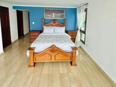 a bedroom with a wooden bed and a blue wall at Beach Front Penthouse in Exclusive Tower in Santo Domingo