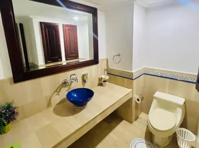 a bathroom with a toilet and a blue bowl on a sink at Beach Front Penthouse in Exclusive Tower in Santo Domingo