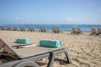 a row of chaise lounges on the beach at Iberostar Waves Costa Dorada - All Inclusive in San Felipe de Puerto Plata