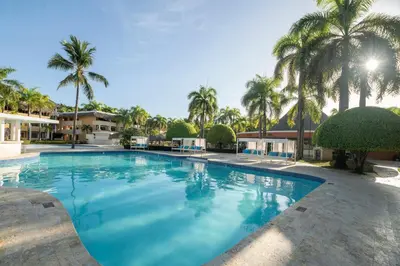 a large swimming pool with palm trees in the background at Iberostar Waves Costa Dorada - All Inclusive in San Felipe de Puerto Plata