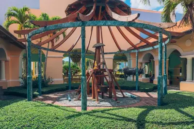 a playground in front of a house with a wooden structure at Iberostar Selection Hacienda Dominicus - All Inclusive in Bayahibe