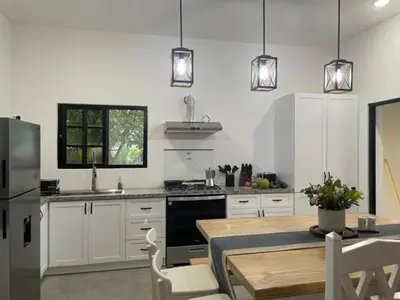 a kitchen with white cabinets and a table and a refrigerator at Villas Elim A and B in Cabrera