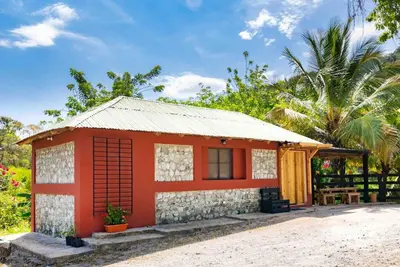 a small red and white house with a palm tree at Hacienda La Huerta, Puerto Plata in San Felipe de Puerto Plata