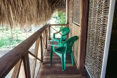 two green chairs sitting on the porch of a house at Parador El Ermitaño in Santa Bárbara de Samaná