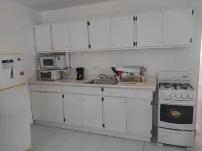 a kitchen with white cabinets and a sink and a stove at Tropical Optimal Tropicana Sur in Sosúa
