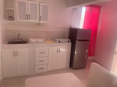 a kitchen with white cabinets and a black refrigerator at Residencial Lucy in Boca Chica