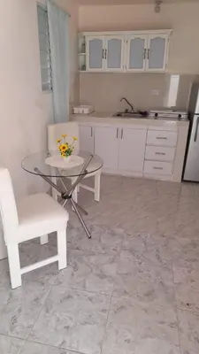 a kitchen with a glass table and a white chair at Residencial Lucy in Boca Chica
