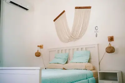 a bedroom with a bed with blue pillows and a window at Sueño Caribeño in La Laguna