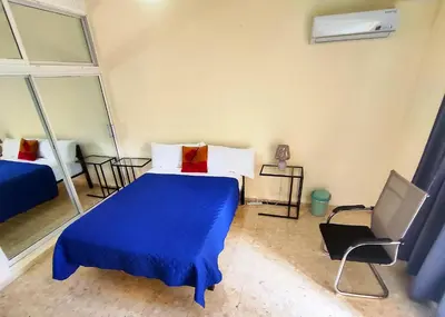 a bedroom with a blue bed and a chair at Refugio Encantador in Santo Domingo