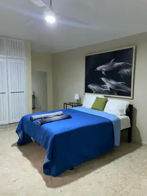 a bedroom with a blue bed with a painting on the wall at Refugio Encantador in Santo Domingo