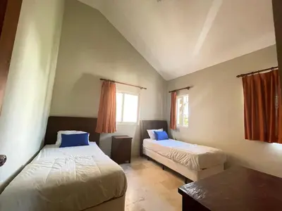a bedroom with two beds and a table and a window at Laguna Golf in Punta Cana