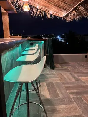 a row of chairs sitting next to a swimming pool at night at Lux Ph & Rooftop Terrace to Relax in Santiago de los Caballeros