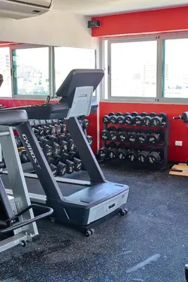 a gym with a treadmill and racks of dumbbells at Central Suites Tower in Santo Domingo