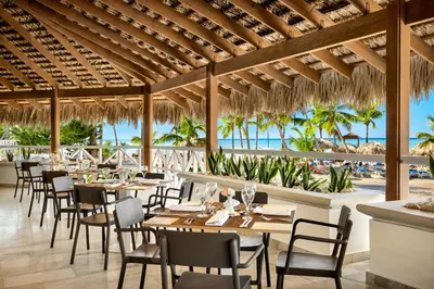 a restaurant with tables and chairs and the ocean at Sunscape Dominicus La Romana - All Inclusive in Bayahibe