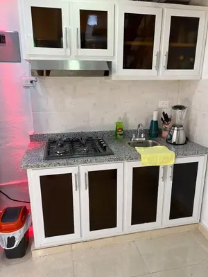 a kitchen with white cabinets and a stove top at Alojamiento paulino in Santiago de los Caballeros