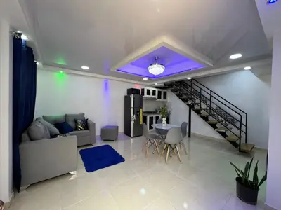 a living room with a couch and a spiral staircase at Alojamiento paulino in Santiago de los Caballeros