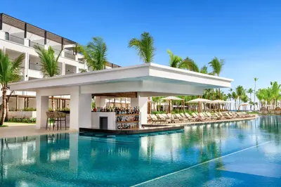 a hotel swimming pool with a bar in front of a building at Secrets Tides Punta Cana - All Inclusive in Punta Cana