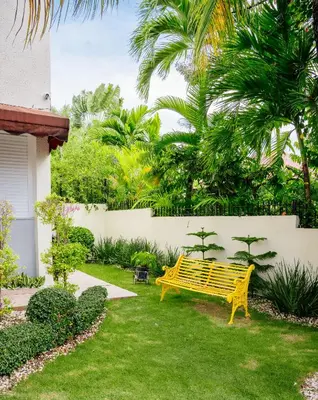 a yellow bench in a yard with palm trees at Habitación privada en Puerto Plata Bayardo in San Felipe de Puerto Plata