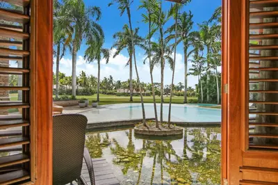 a view of a pool with palm trees from a door at Luxurious 8-BR Villa with Ocean View, Jacuzzi, Home Cinema and Resort Access in Casa de Campo in La Romana