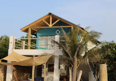 a house with a hammock in front of a palm tree at Villas El Bucanero in San Felipe de Puerto Plata