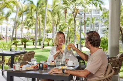 a man and woman sitting at a table drinking champagne at Riu Palace Macao - Adults Only - All Inclusive in Punta Cana