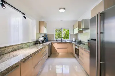 a large kitchen with wooden cabinets and stainless steel appliances at Stunning 3-Bedroom Villa with Pool, Jacuzzi and Maid near Bavaro Beach in Punta Cana