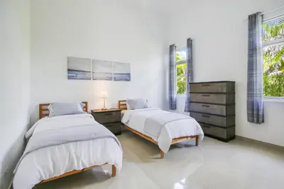 a bedroom with two beds and a dresser and two windows at Stunning 3-Bedroom Villa with Pool, Jacuzzi and Maid near Bavaro Beach in Punta Cana
