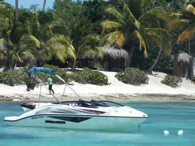 a man is standing on a speed boat in the water at Appartamenti in Cadaques Caribe in Bayahibe