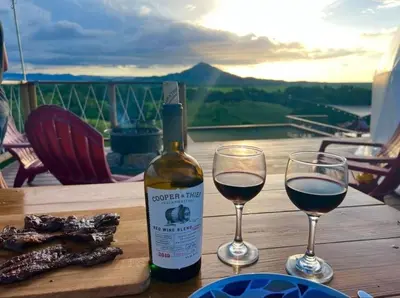 a bottle of wine and two wine glasses on a table at Domescape Glamping in El Cedro