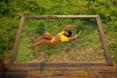 a woman in a yellow bikini jumping on a net at Domescape Glamping in El Cedro