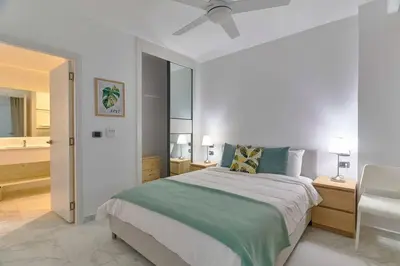 a white bedroom with a bed and a bathroom at Luxury Apartment at Cana Rock Star Punta Cana DR in Punta Cana