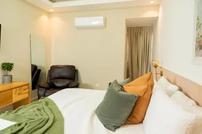 a bedroom with a bed and a chair at Hotel Stay Here Suites in Santo Domingo