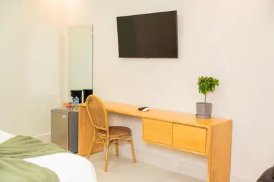 a bedroom with a desk with a tv on a wall at Hotel Stay Here Suites in Santo Domingo