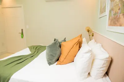 a bedroom with a bed with pillows on it at Hotel Stay Here Suites in Santo Domingo