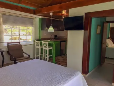 a bedroom with a white bed and a green kitchen at Sava Salinas in Las Salinas