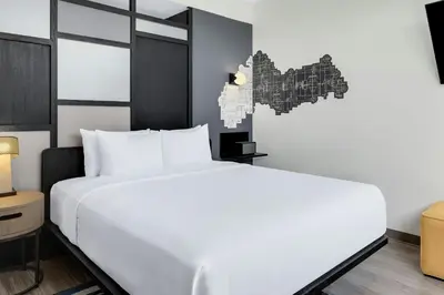 a bedroom with a large white bed and a map at Aloft Santo Domingo Piantini in Santo Domingo