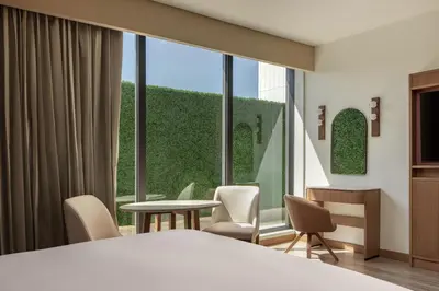 a room with a bed and chairs and a large window at Santo Domingo Marriott Hotel Piantini in Santo Domingo