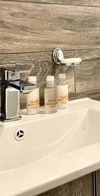a white bathroom sink with four bottles on it at Luxury 1 BDR , Rooftop POOL, Gym, in Downtown D2 in Santo Domingo